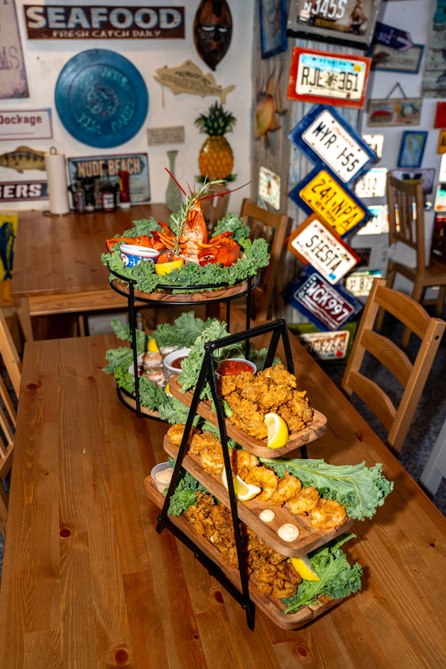 A tiered seafood tower of fried shrimp, oysters and lobster on a wooden table