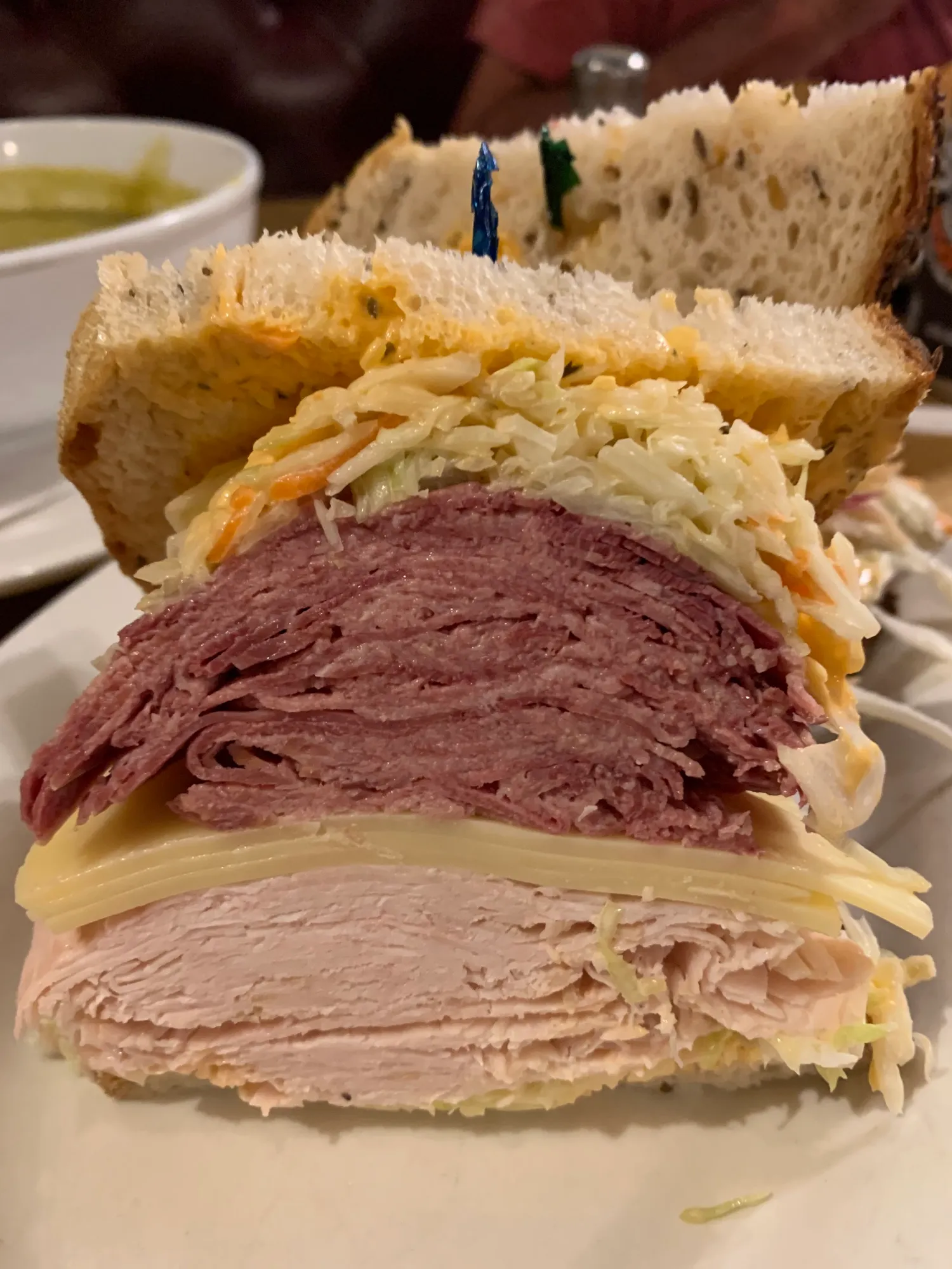 A stacked deli sandwich on rye with corned beef, turkey, Swiss and coleslaw